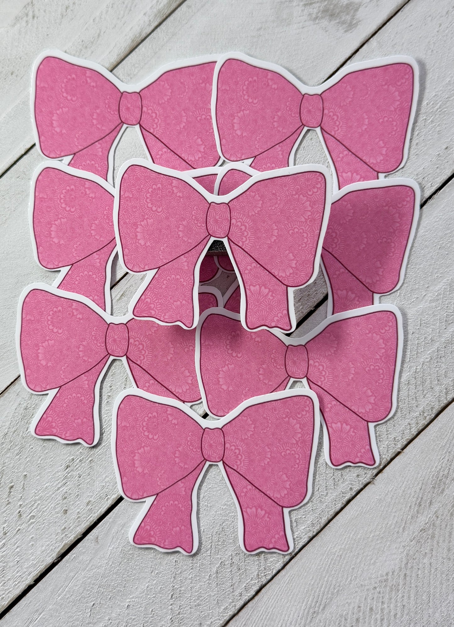 Pink bow-shaped stickers on a wooden surface