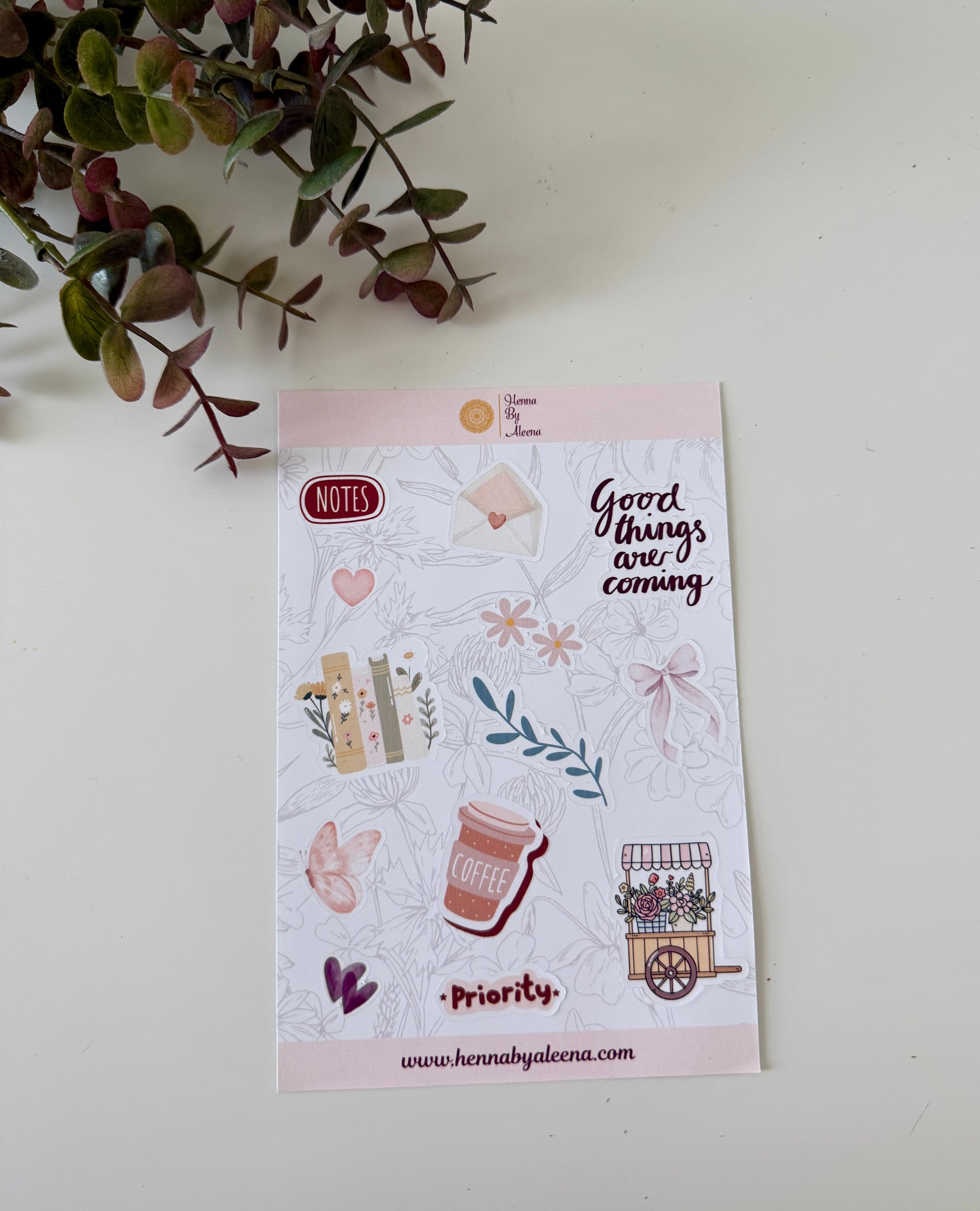 Sheet of decorative stickers with illustrations and text on a white surface with a plant in the corner.