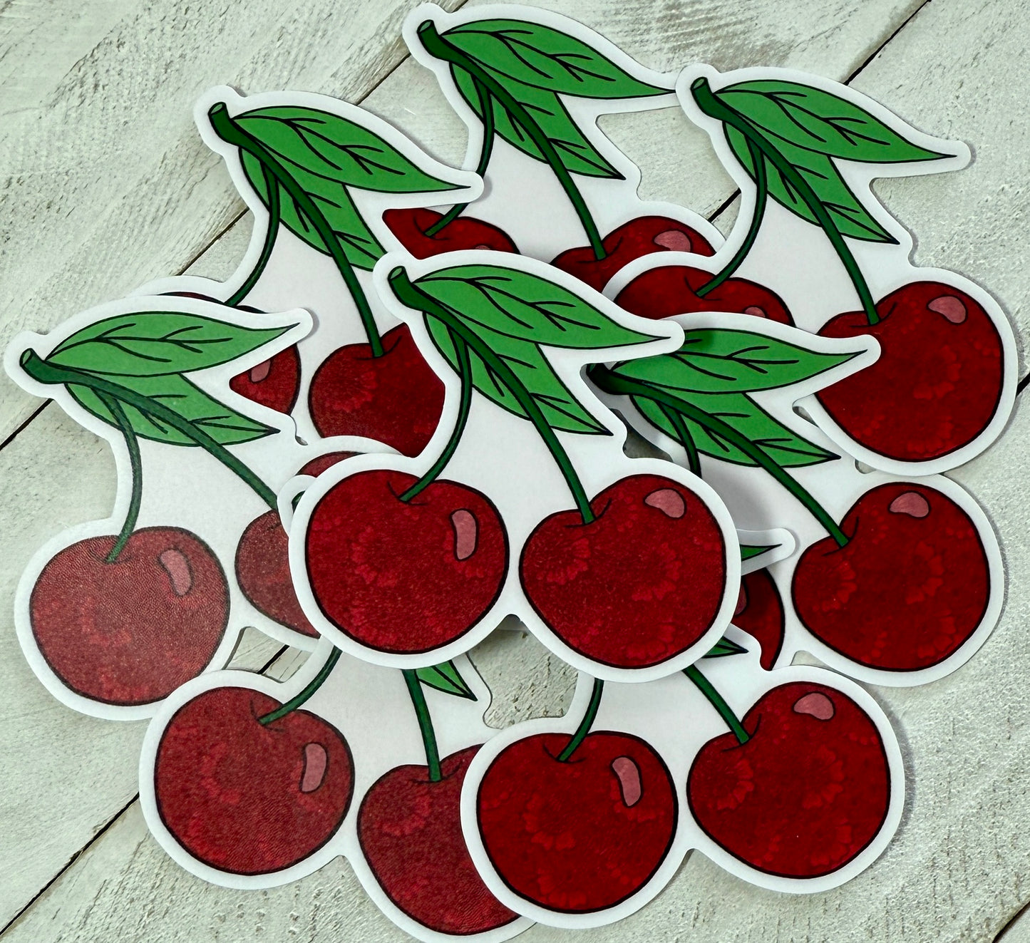 A collection of sticker depicting red cherries with green leaves on a white background.
