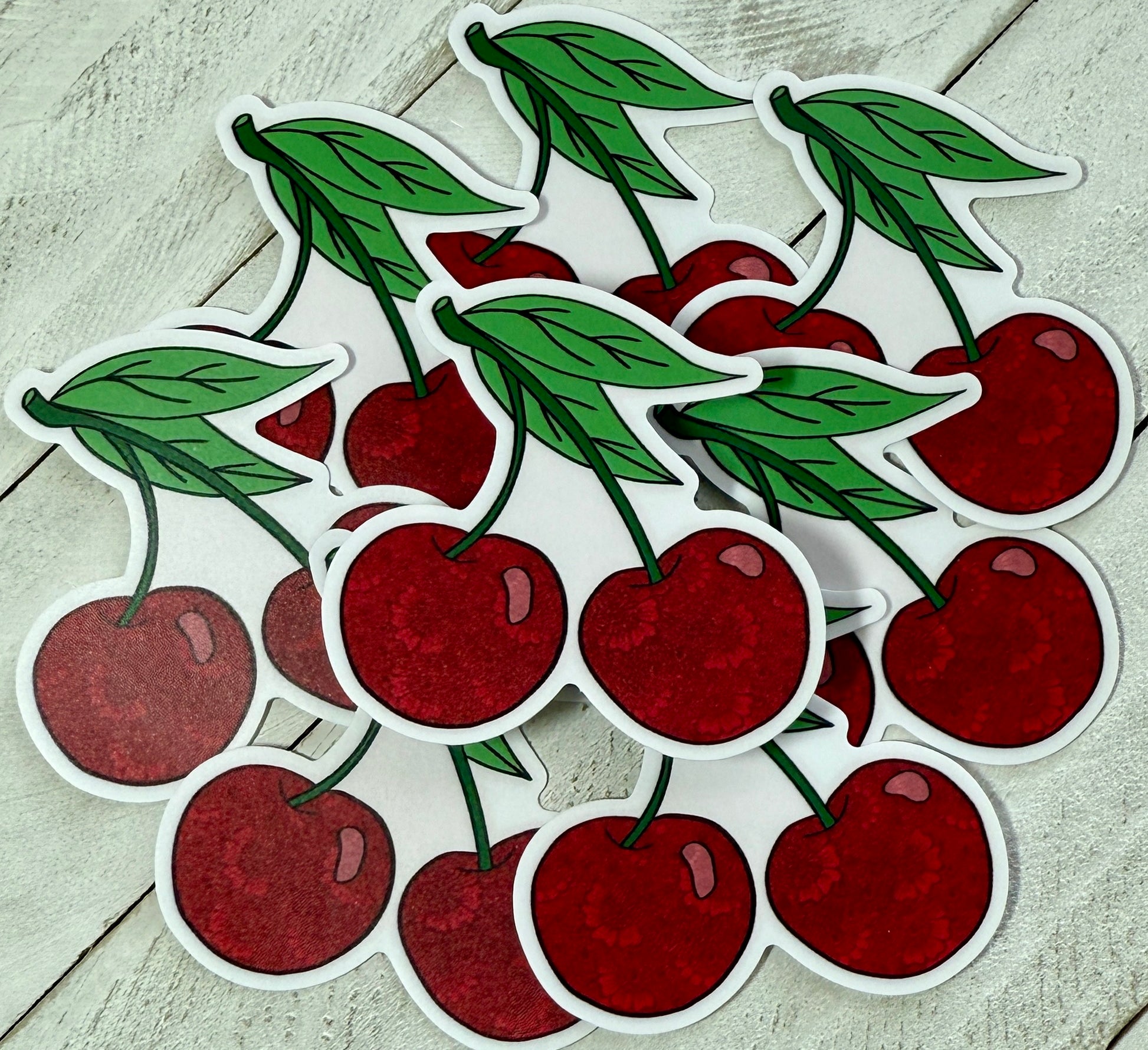 A collection of sticker depicting red cherries with green leaves on a white background.