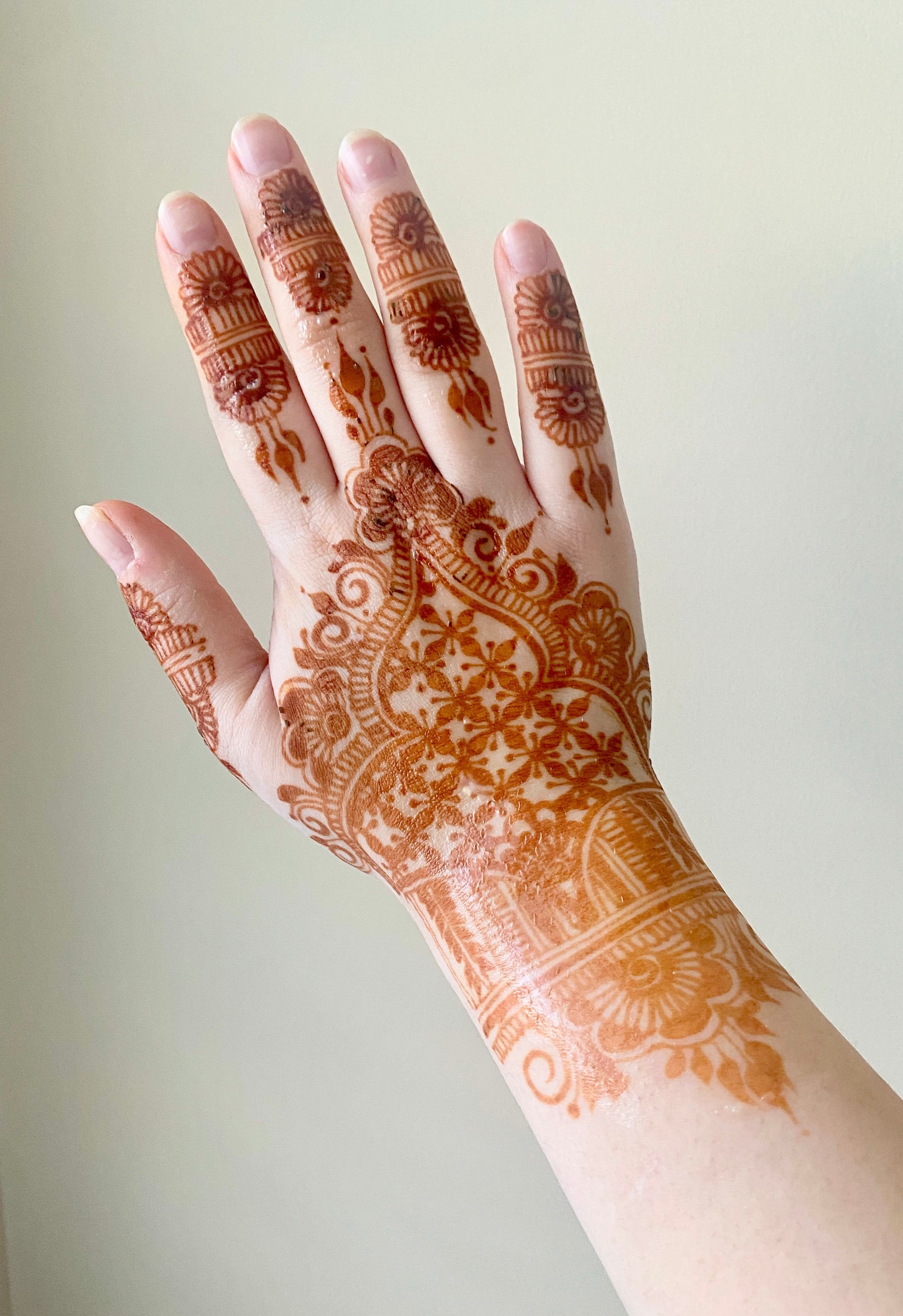 A hand depicting a light orange/brown henna stain 