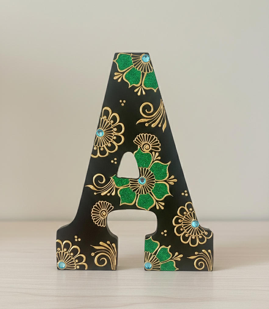 Decorative letter 'A' with green and gold henna design on a white background