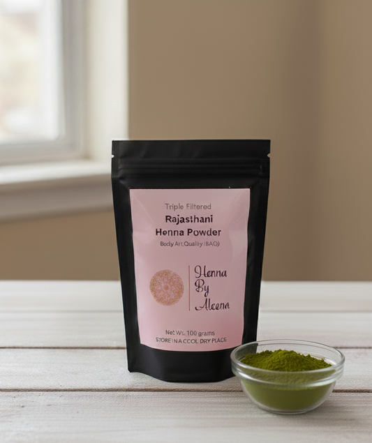 Packaging of Rajasthani Henna Powder with a small bowl of green henna powder on a wooden surface.
