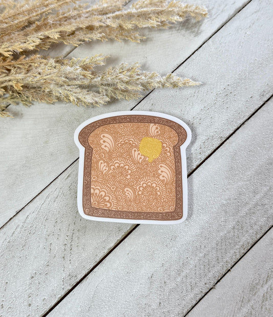 Sticker of a slice of bread with a pattern on a wooden surface with dried plants.