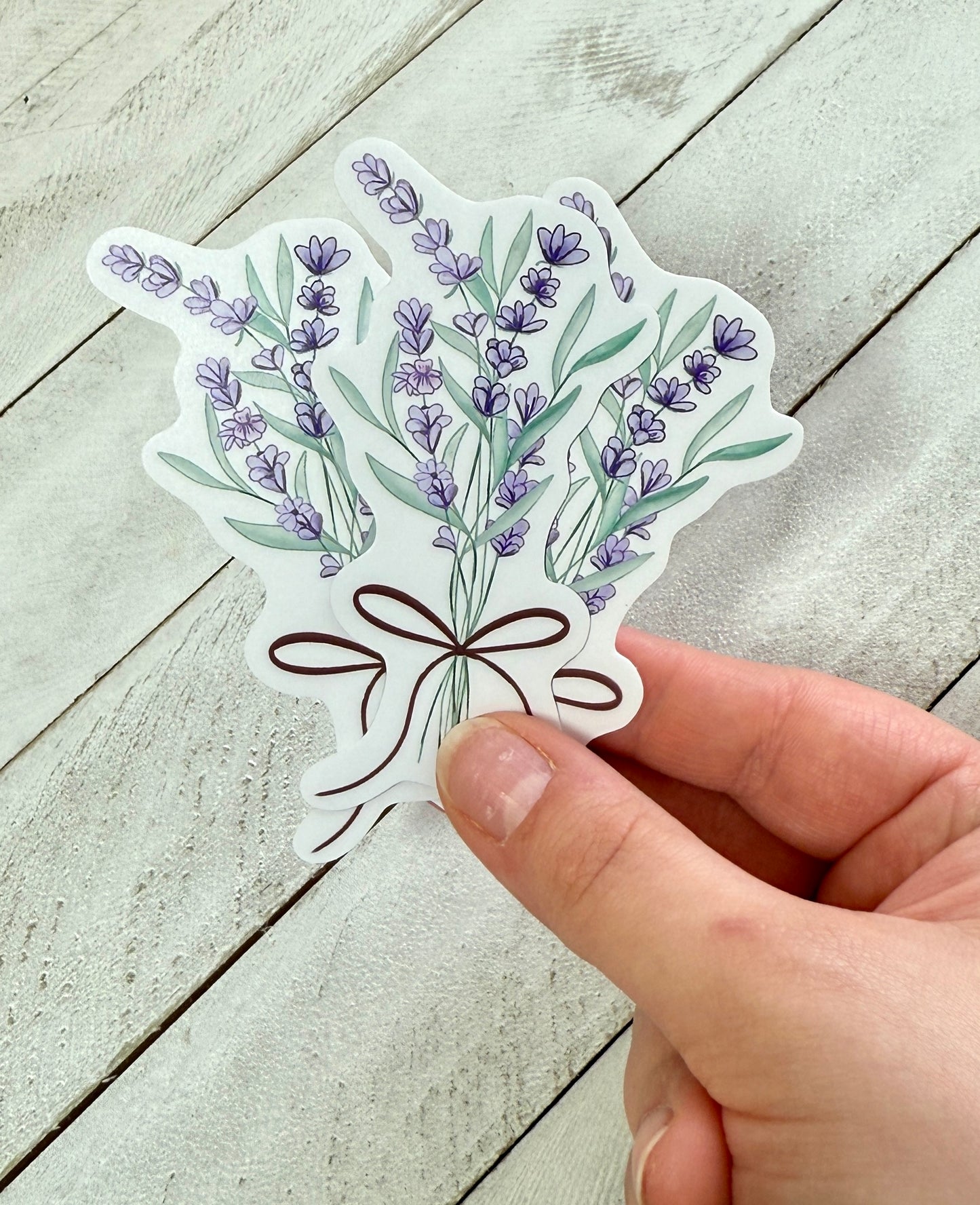 Hand holding stickers of lavender flowers on a wooden surface