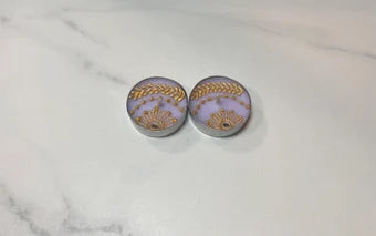 Two tea light candles with a lavender color and gold henna design, placed on a marble surface.