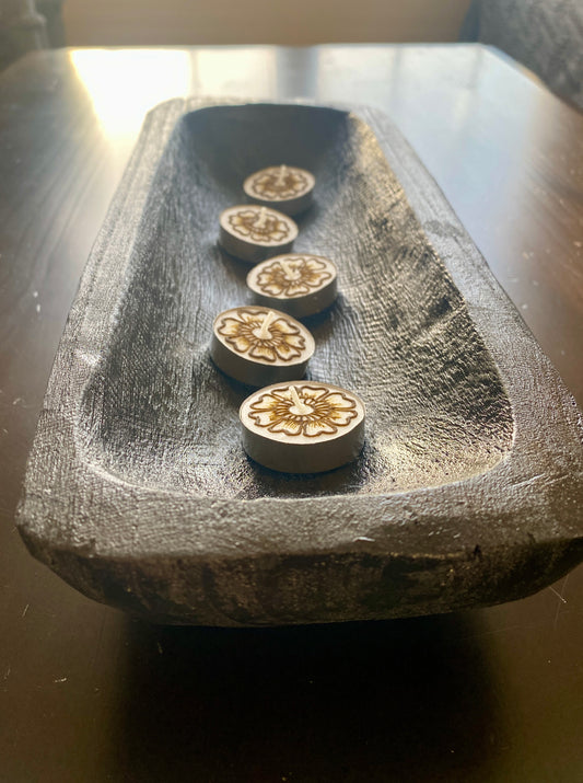A set of five hand-painted tea lights with henna in a dark, textured candle holder.