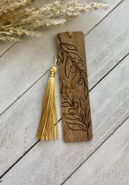 Olive branch bookmark with a golden tassel on a wood background 
