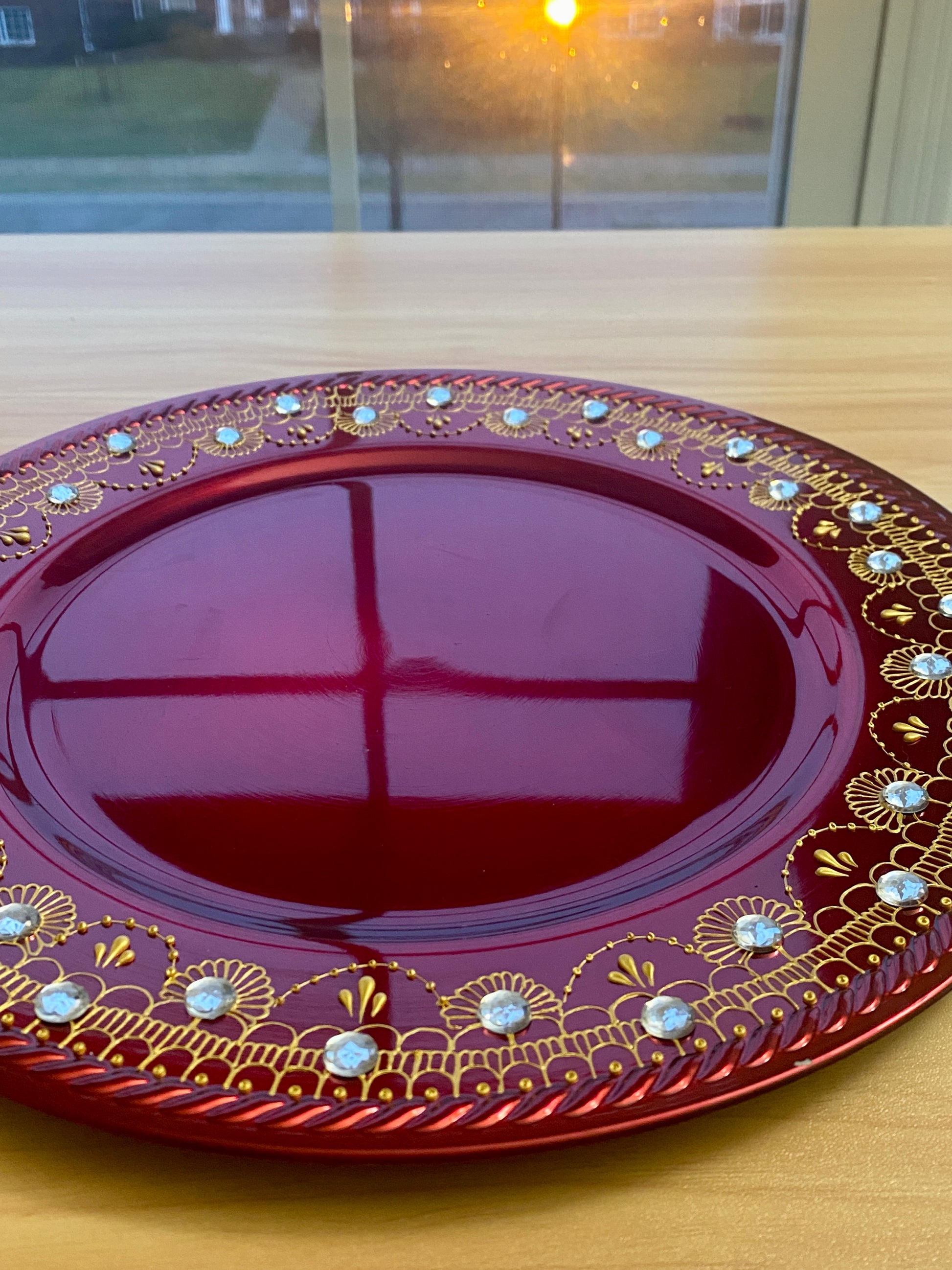Red charger plate with gold henna detailing and rhinestones. 