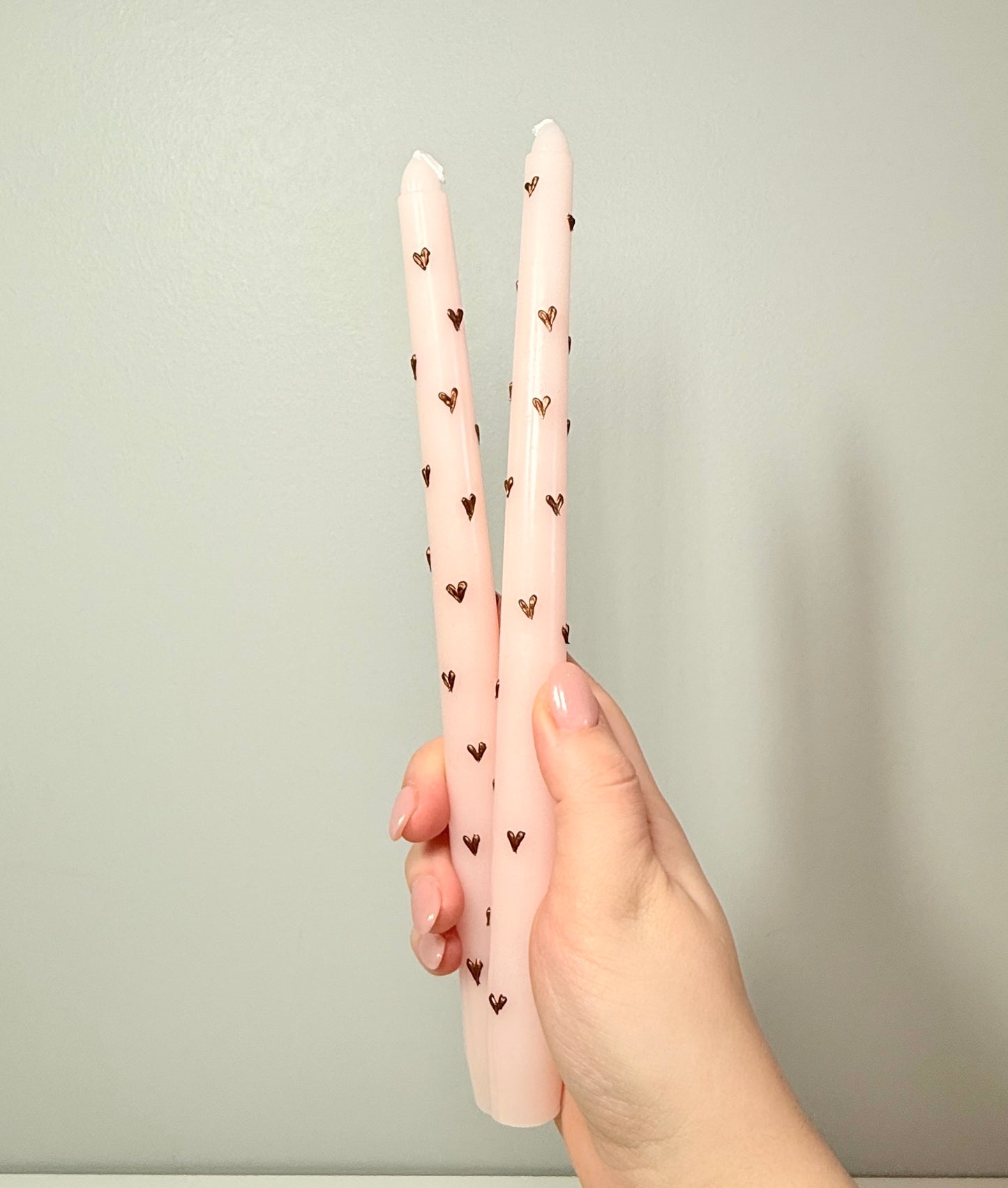 Two light pink tapered candles with bronze hearts 