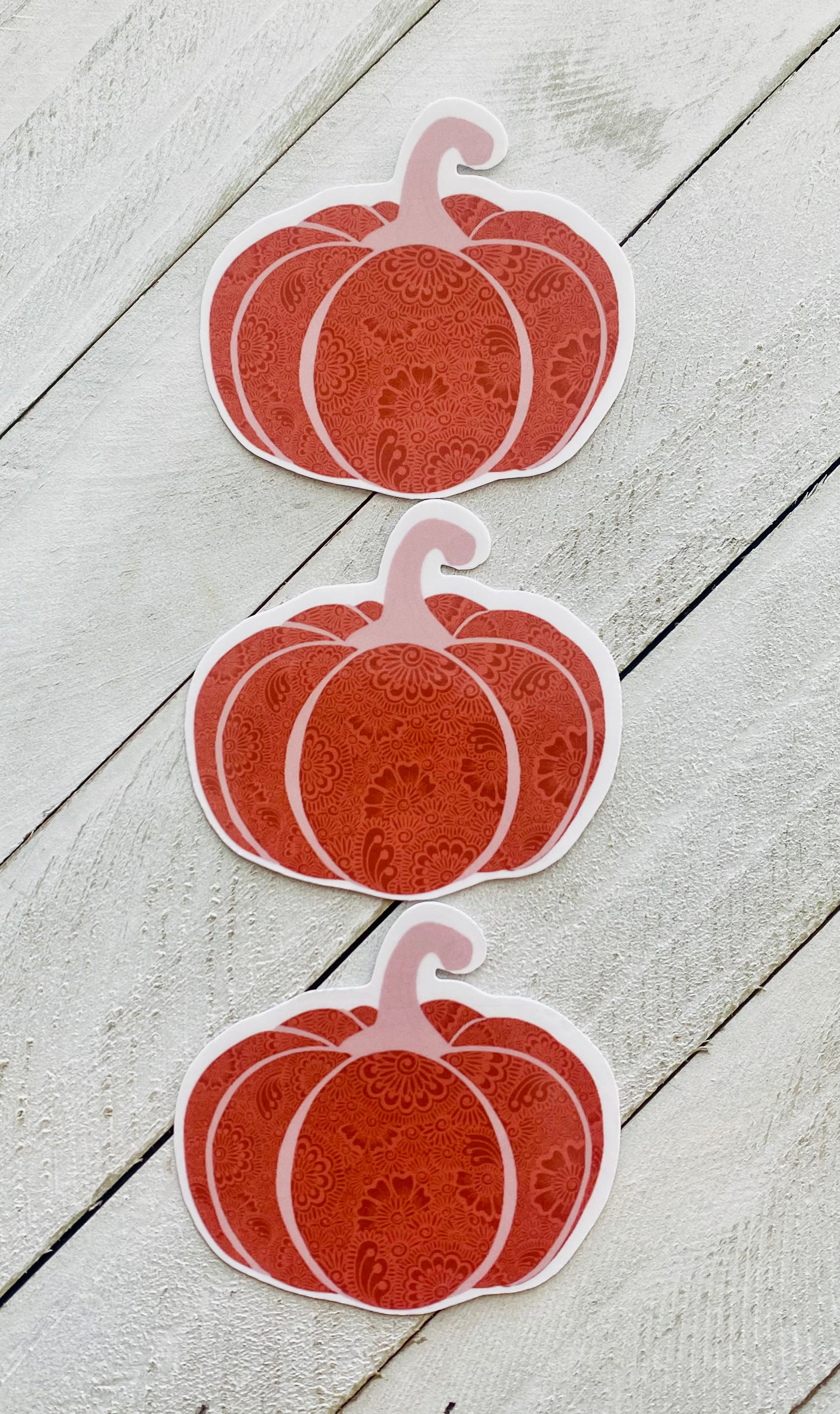 Three henna pumpkin stickers placed in a row over a wood background 